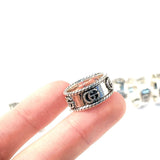 Silver ring with a Gucci logo on a finger against a white background