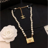 Pearl necklace with gold CC pendant on a black background