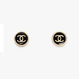 Pair of Chanel earrings with black and gold logo on a white background