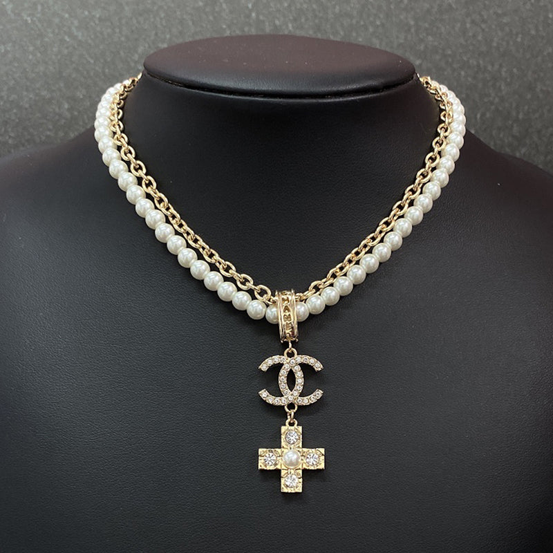 Pearl necklace with a diamond cross pendant on a black mannequin against a gray background