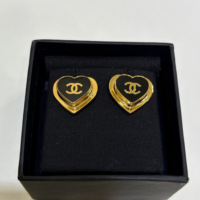 Heart-shaped earrings with gold border and black center logo in a black box.