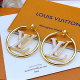 Gold hoop earrings with 'LV' logo on a Louis Vuitton box